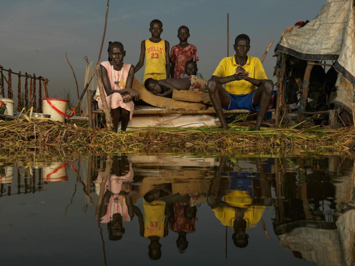 Adit Kak and her family sit on their floating home. Although they are able to catch fish, they live in isolaton since the flood water ook their old home in October. " We lost everything in the floods but we do not want to leave this place. We have lived here all our lives and call this place home" says Adit.