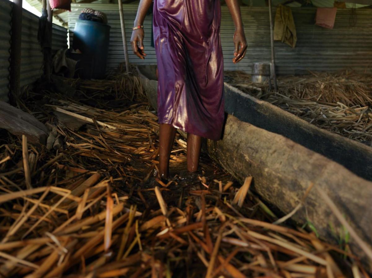 Nyayiena at home in the background is an abandoned classroom. She is living on a floating pontoon. By tightly packing many layers of grass on top of one another, the floor becomes a floating floor that will rise and fall with the flood water.