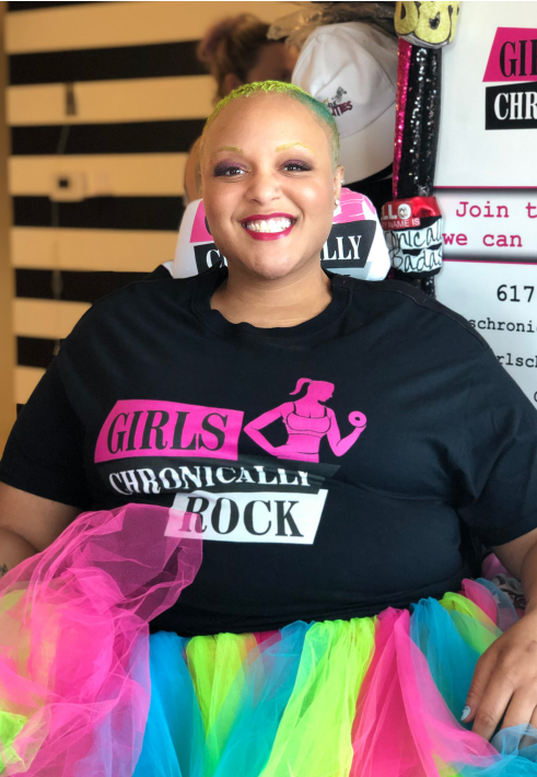 A person in a colorful tutu and black tshirt with "Girls Chronically Rock".