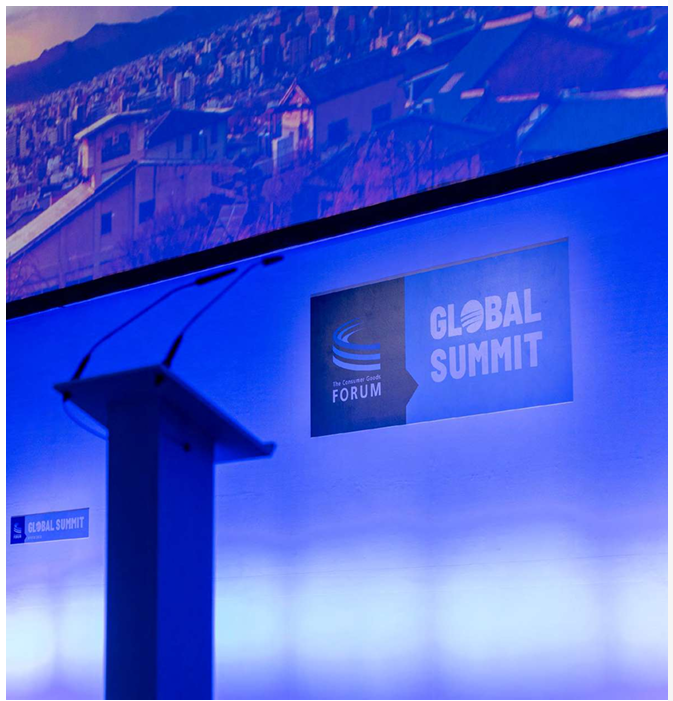 An empty podium on a stage. "Global Summit" and The consumer goods forum logo behind it.