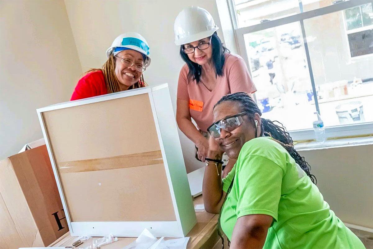 Three people putting together drawers inside a house.