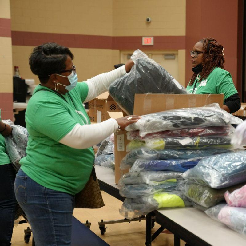 International Paper volunteers place coats on school cafeteria tables
