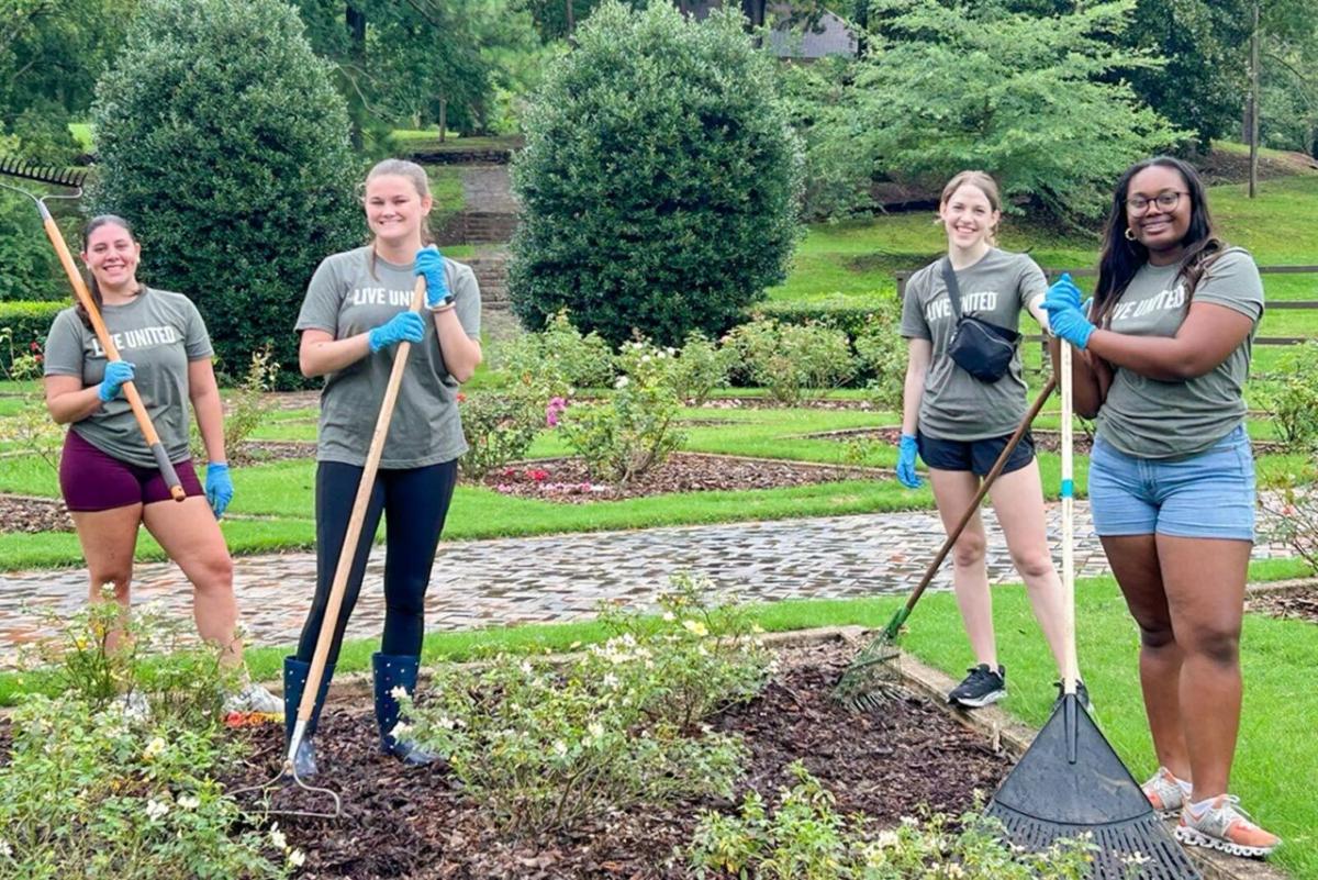 A group of volunteers posed with garden tools.