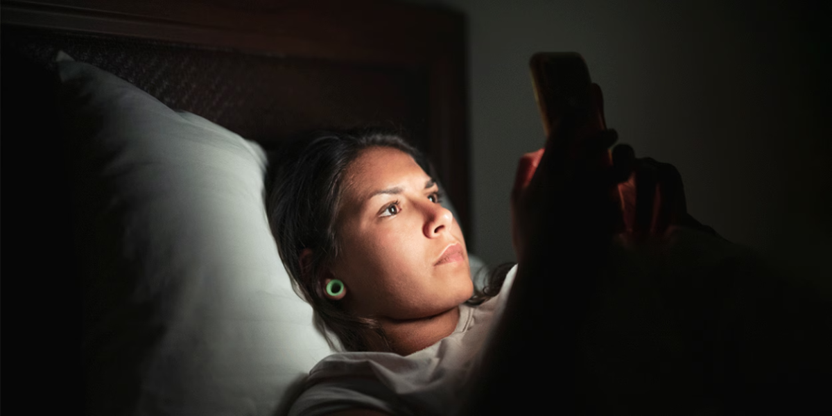 person looking at smartphone at night in bed