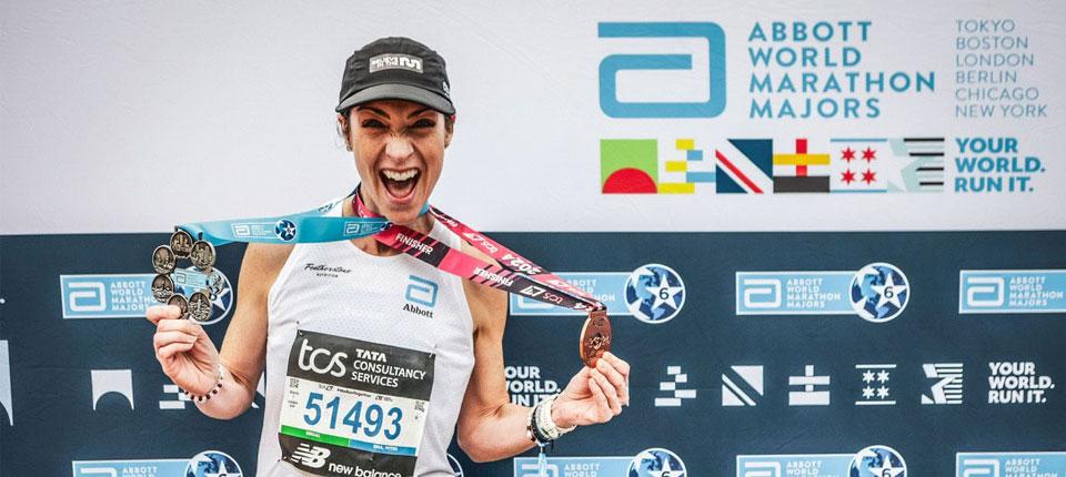 A person wearing medals in front of an Abbott World Marathon Majors back drop 