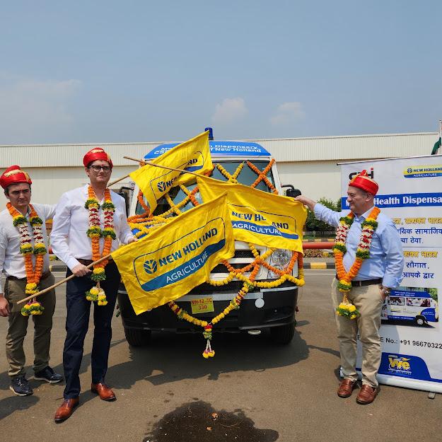 New Holland employees holding flags in front of the new mobile medical dispensary van