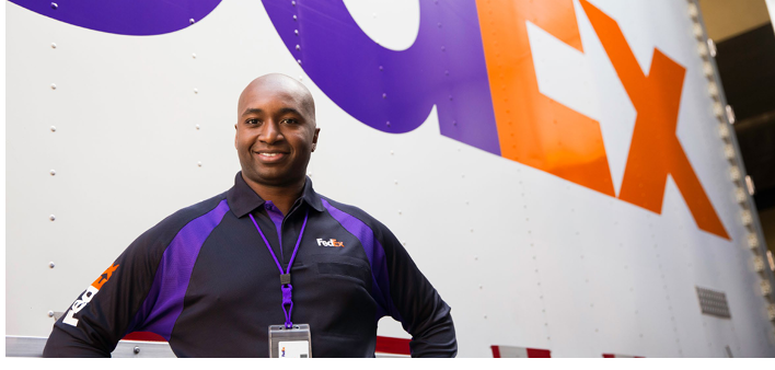 A person posed in front of a truck with "FedEx" on the side.