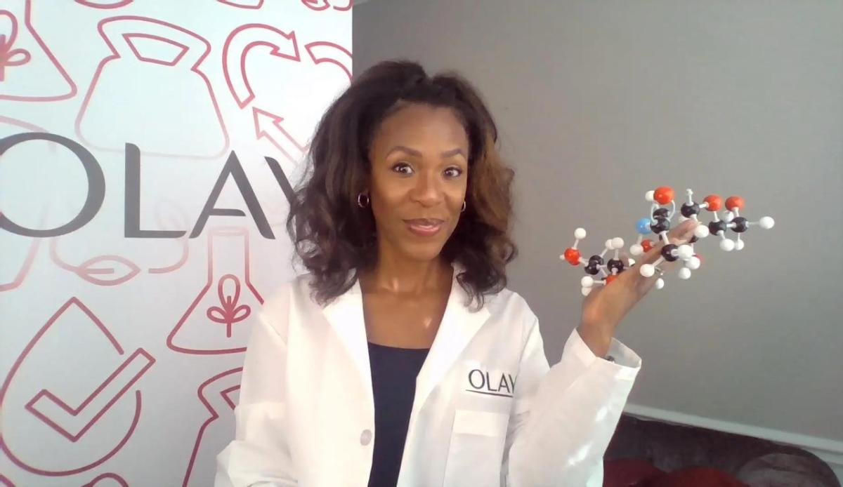 A person in a lab coat holding a molecular model.