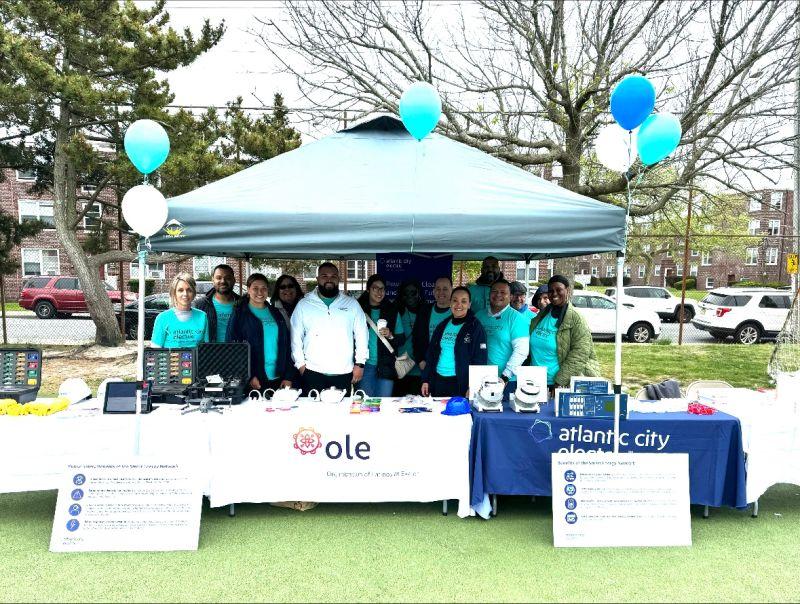 A group of volunteers posed under a tent and booths outside.