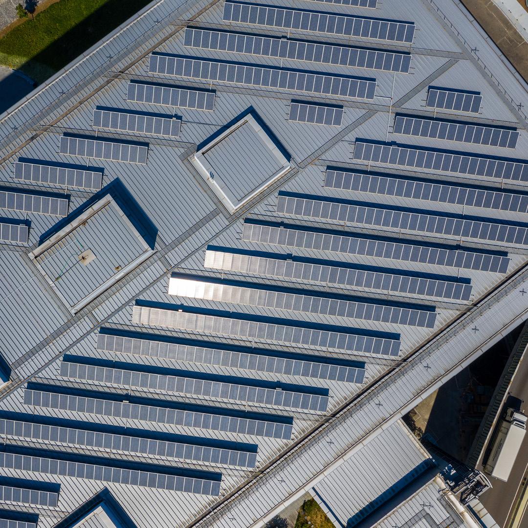 Aerial view of large rows of solar panels on a rooftop.