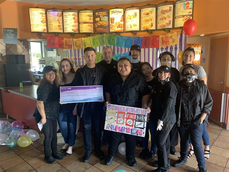 Andrew German with his work crew, holding an oversized check