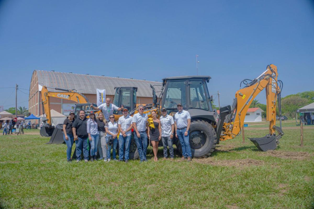 A team of people posed in front of two digging-type construction vehicles