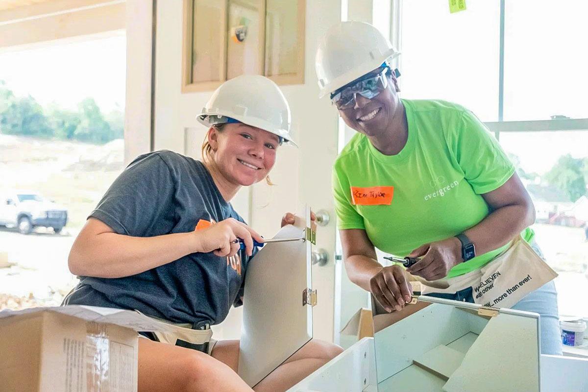 Two smiling people building.