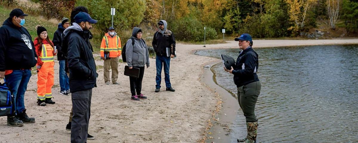 group of people speaking along the edge of a body of water