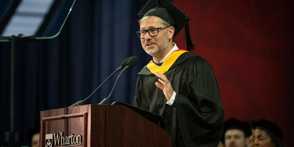 Mike Sievert, CEO of T-Mobile, in a cap and gown at a podium