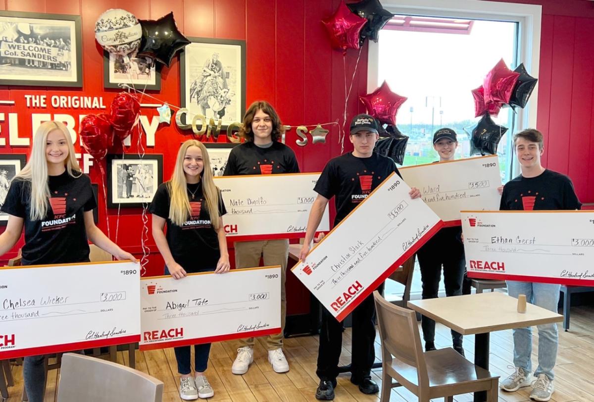 6 students holding big checks