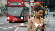 Person wearing wireless earbuds while using a phone with a red buss