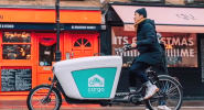 A person on a cargo bike riding past small shops