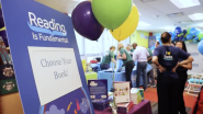 A sign that reads "choose your book!" on an event stand with balloons 