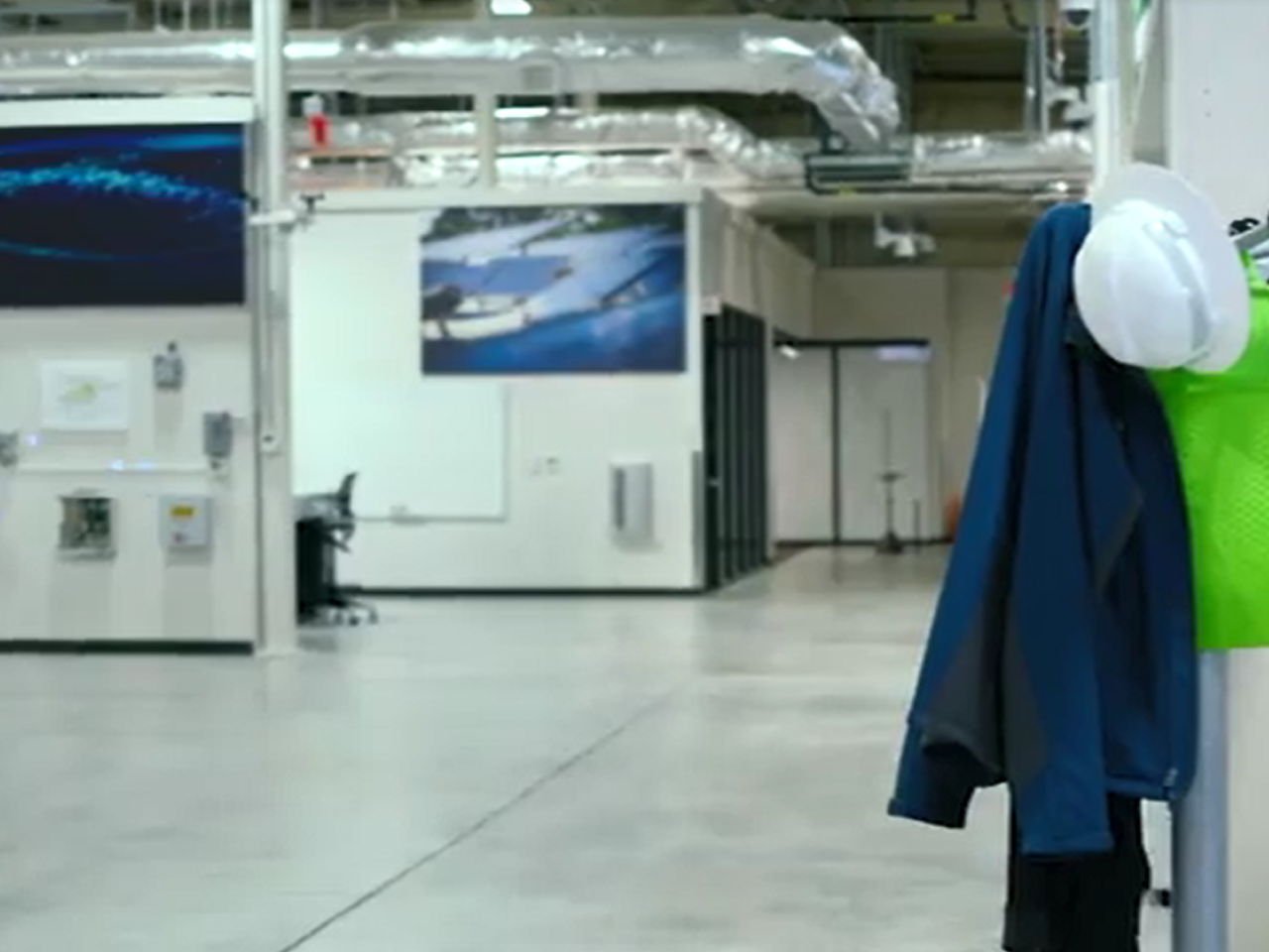 An empty industrial room, coat and hardhat on a stand.