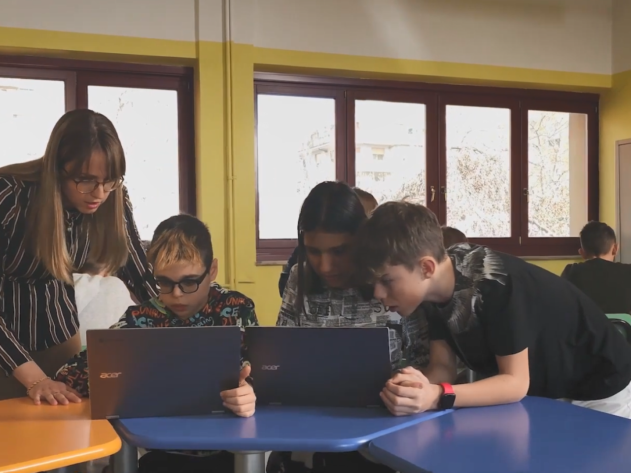 Students and a teacher in a classroom using laptop computers.