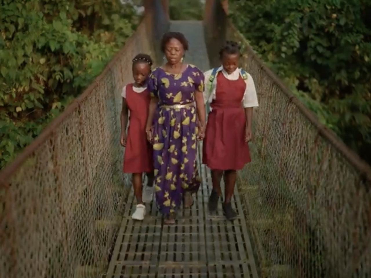 Woman walking across a bridge with her two young daughters