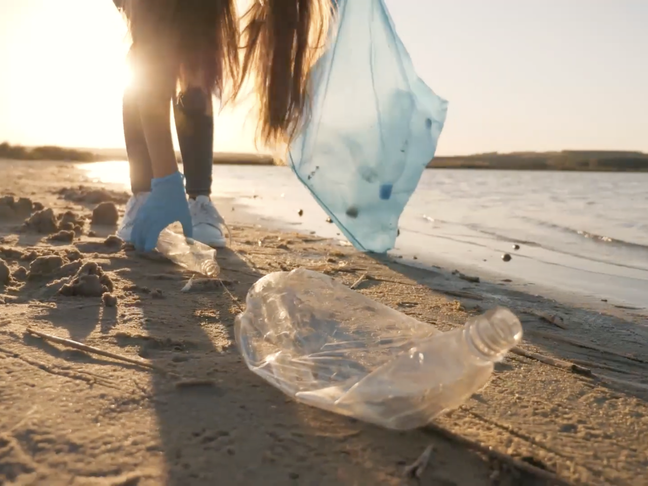 A person picking up plastic waste on a beach