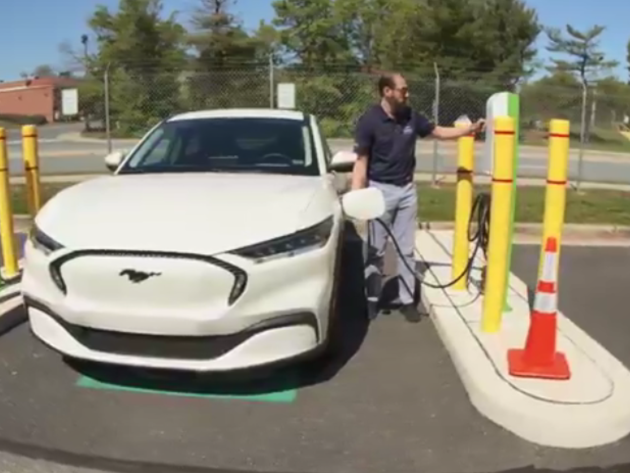 A person next to a vehicle and charging station