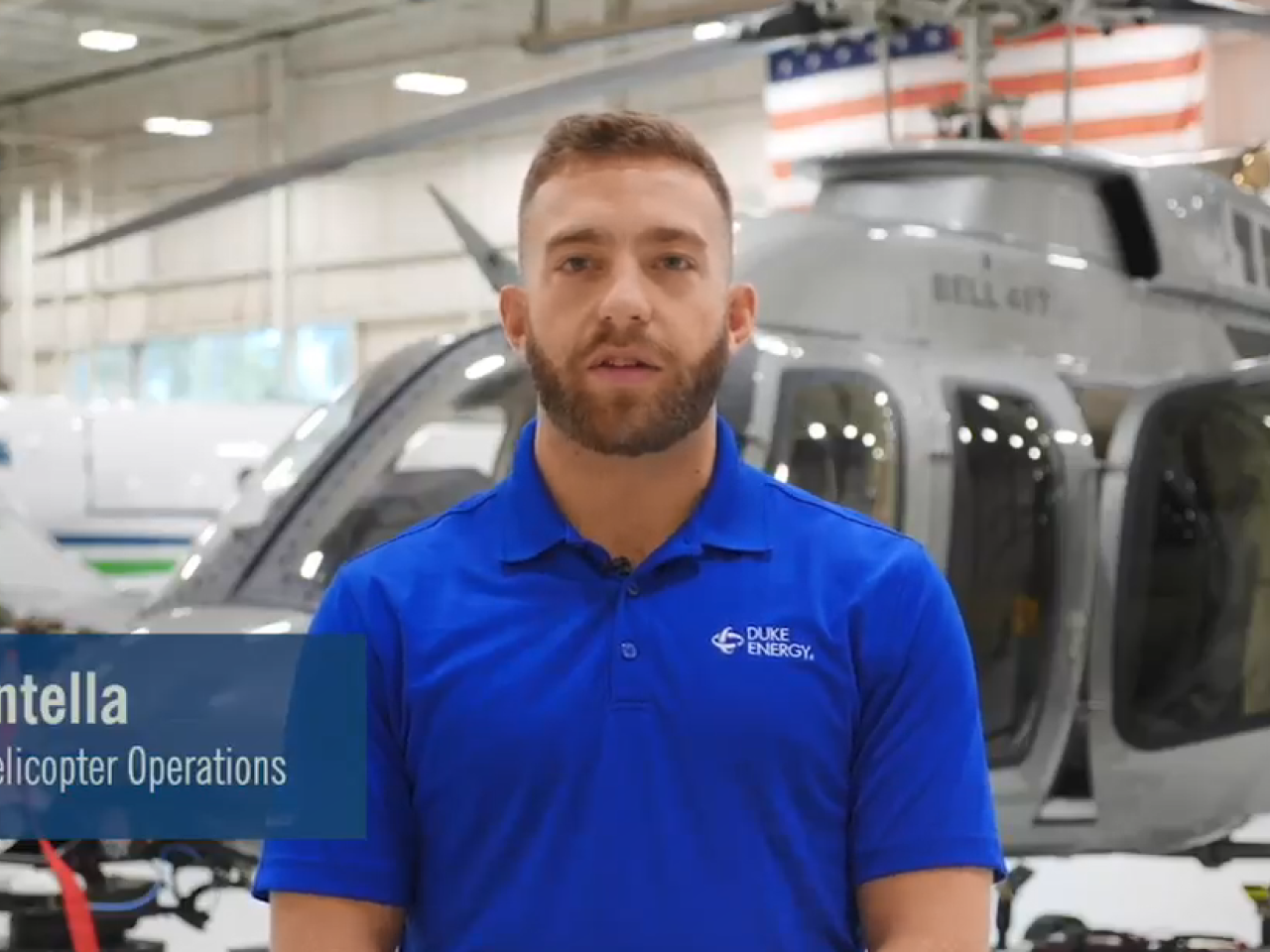 A Duke Energy employee interviewed in front of a helicopter in a hanger. 