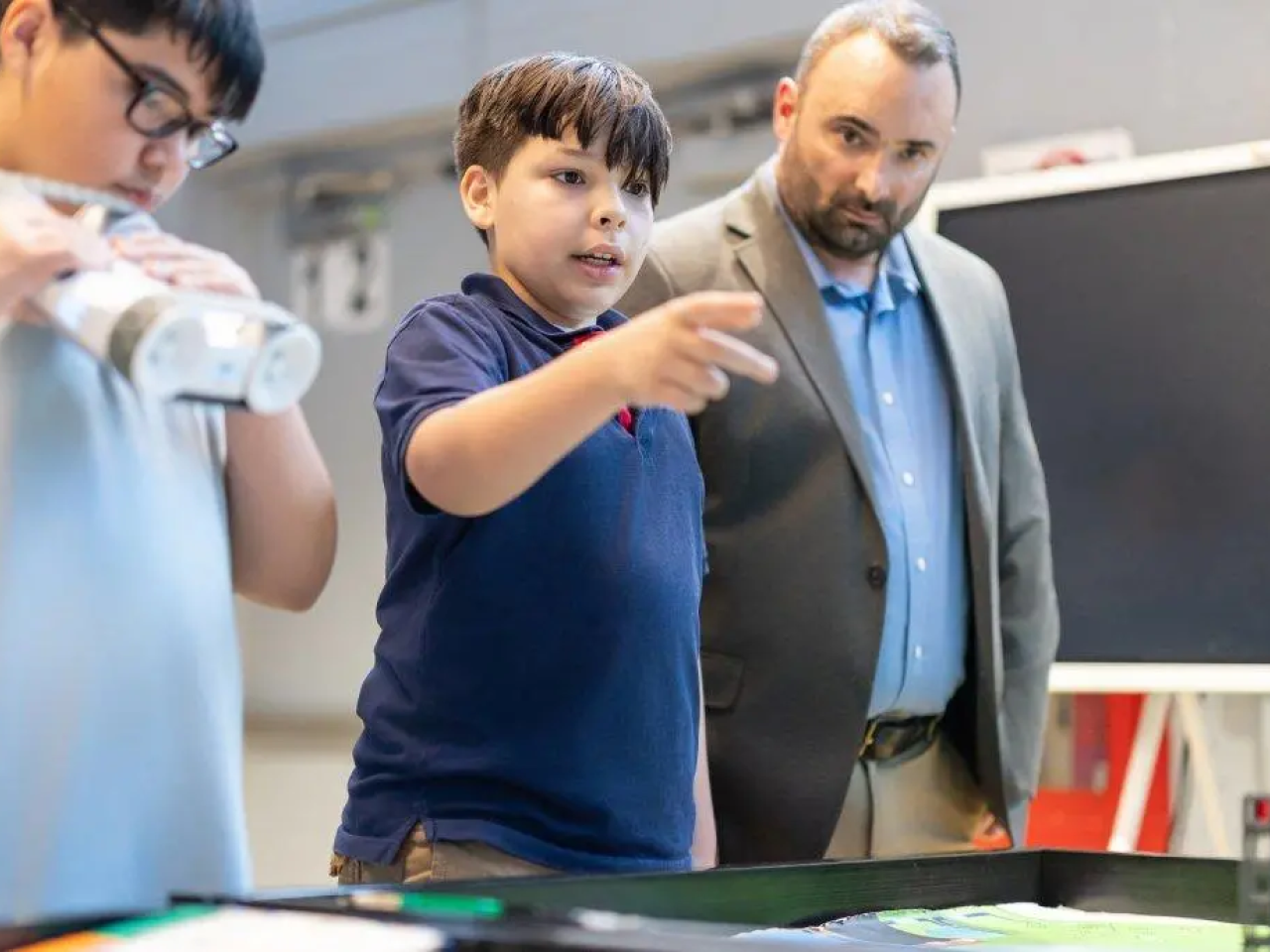 Greg Pardo looks over two students