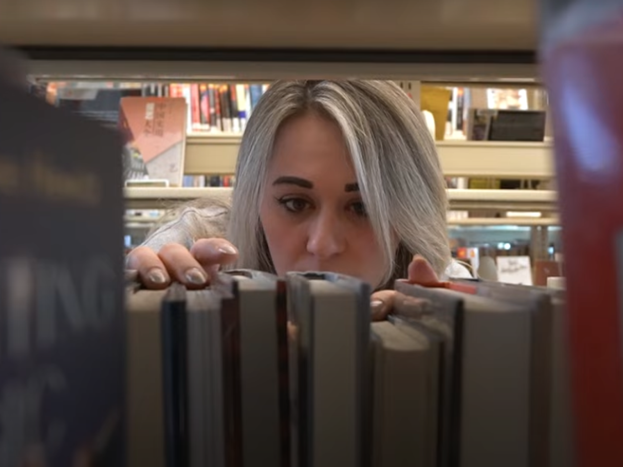 Someone looking through a bookshelf