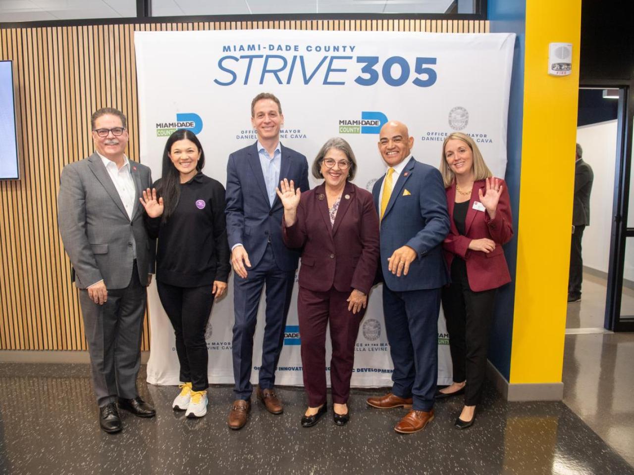 6 men and women standing in front of a sign that says "Strive 305"