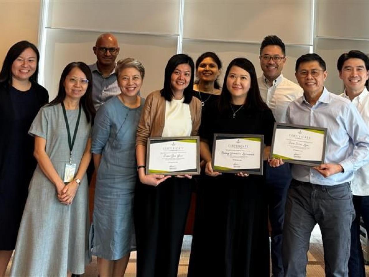 A group of people standing together, holding diplomas