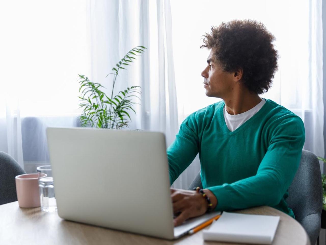Man sitting at a desk looking towards a window