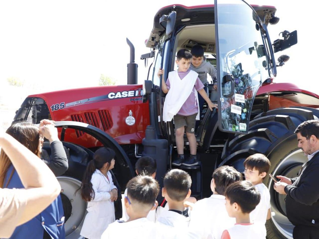 Children looking at and climbing into red tractor