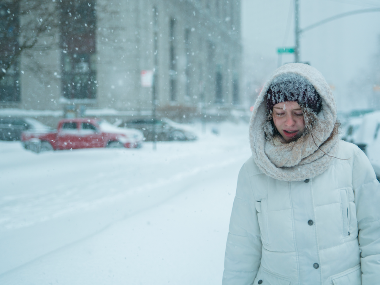 Woman shown in an extreme snow storm in a city.