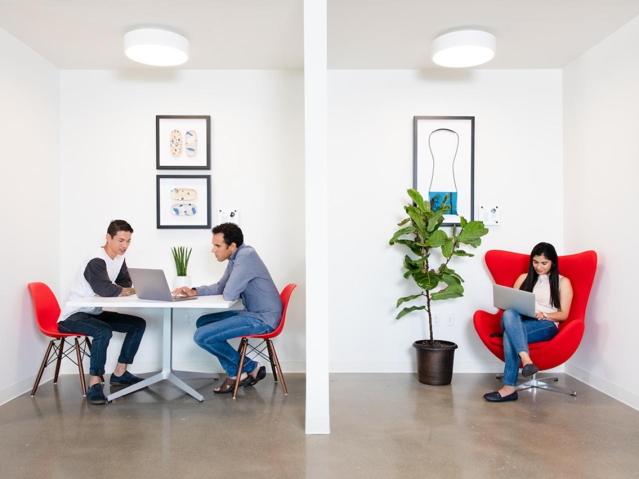 Three people seated and working on laptops.