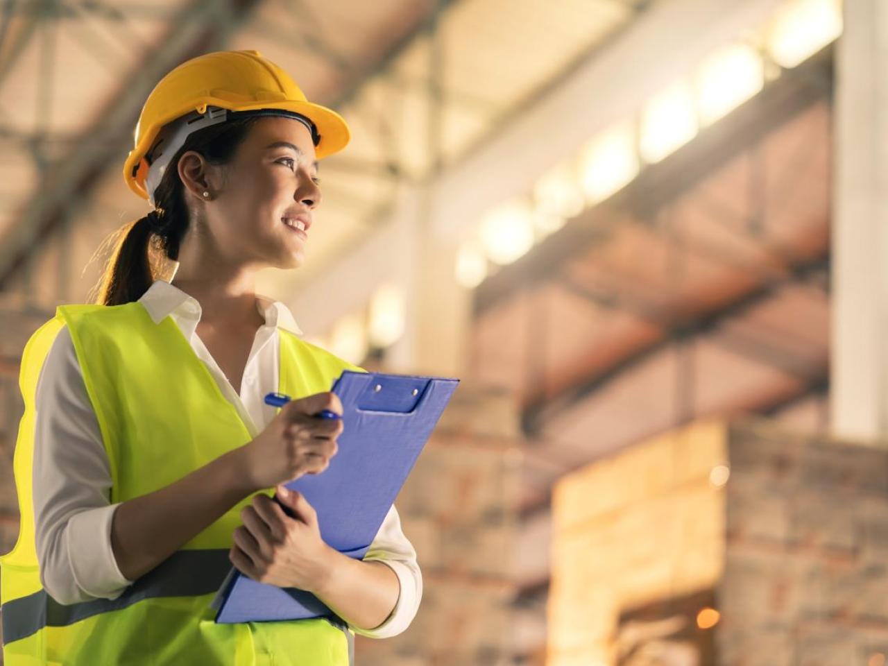 Woman wearing hard hat and holding clipboard