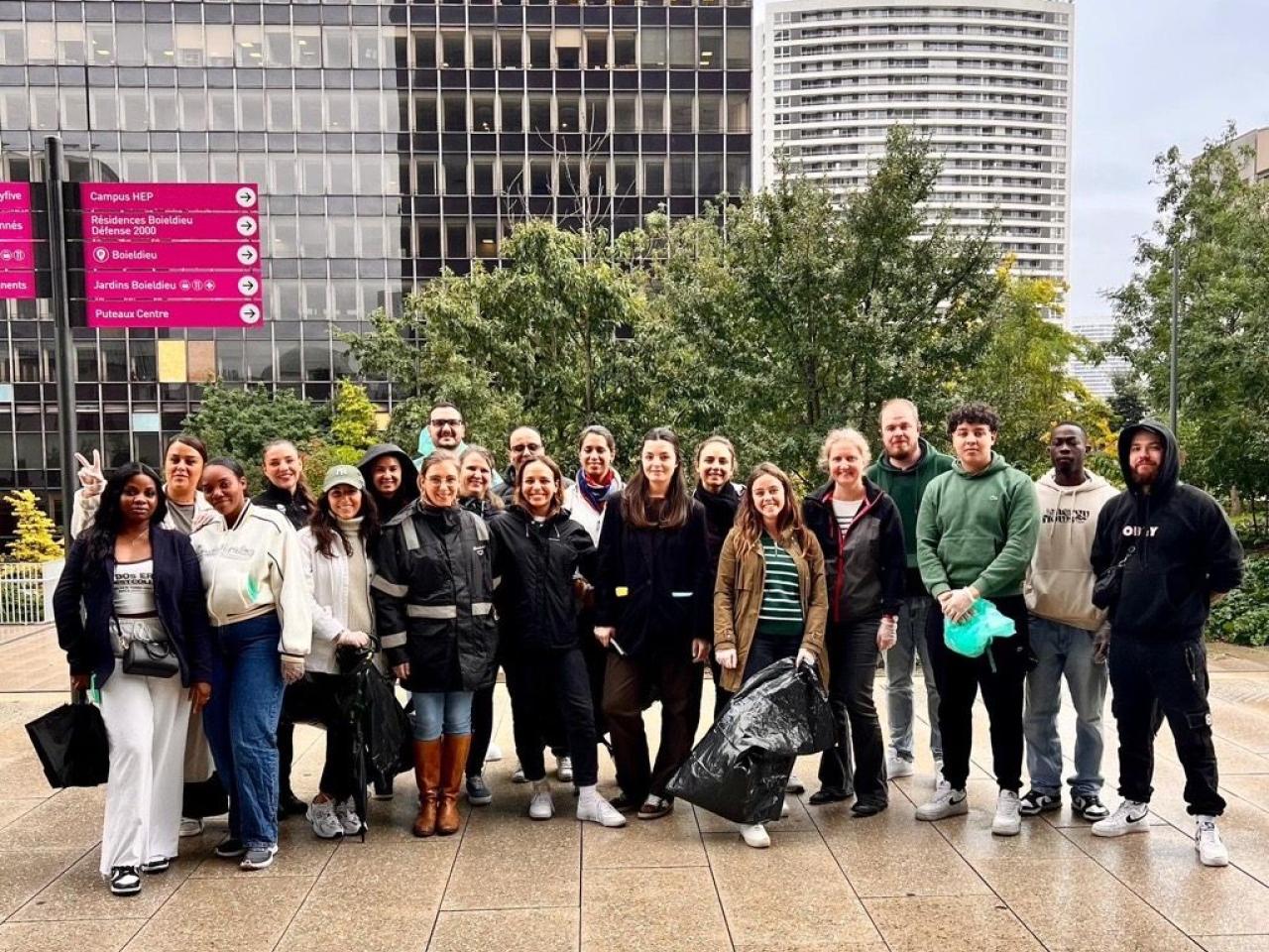 S group posed together outside. Some holding black trash bags.