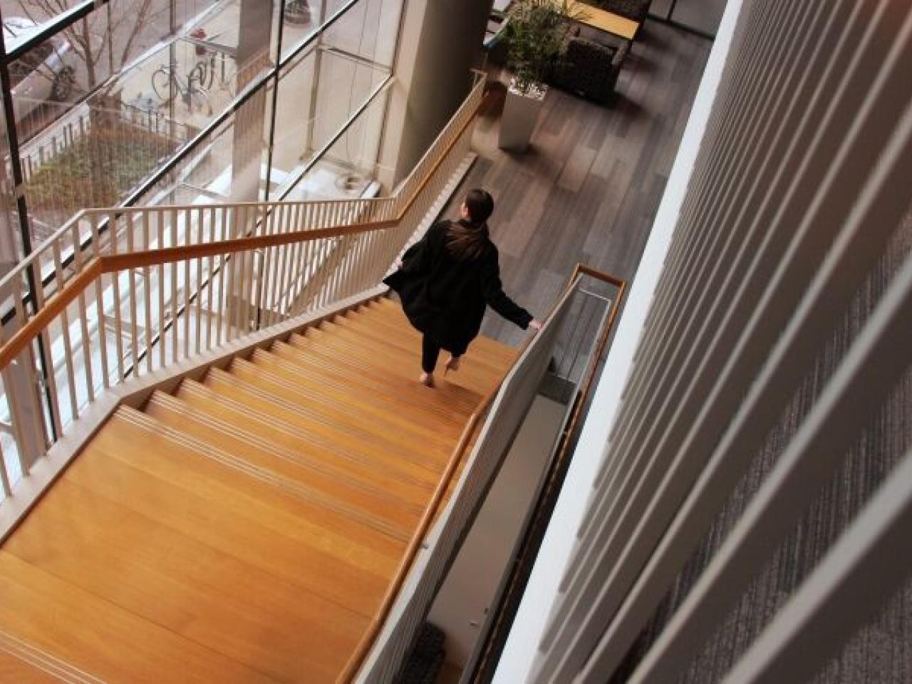 A person walking down a long, wooden, staircase.