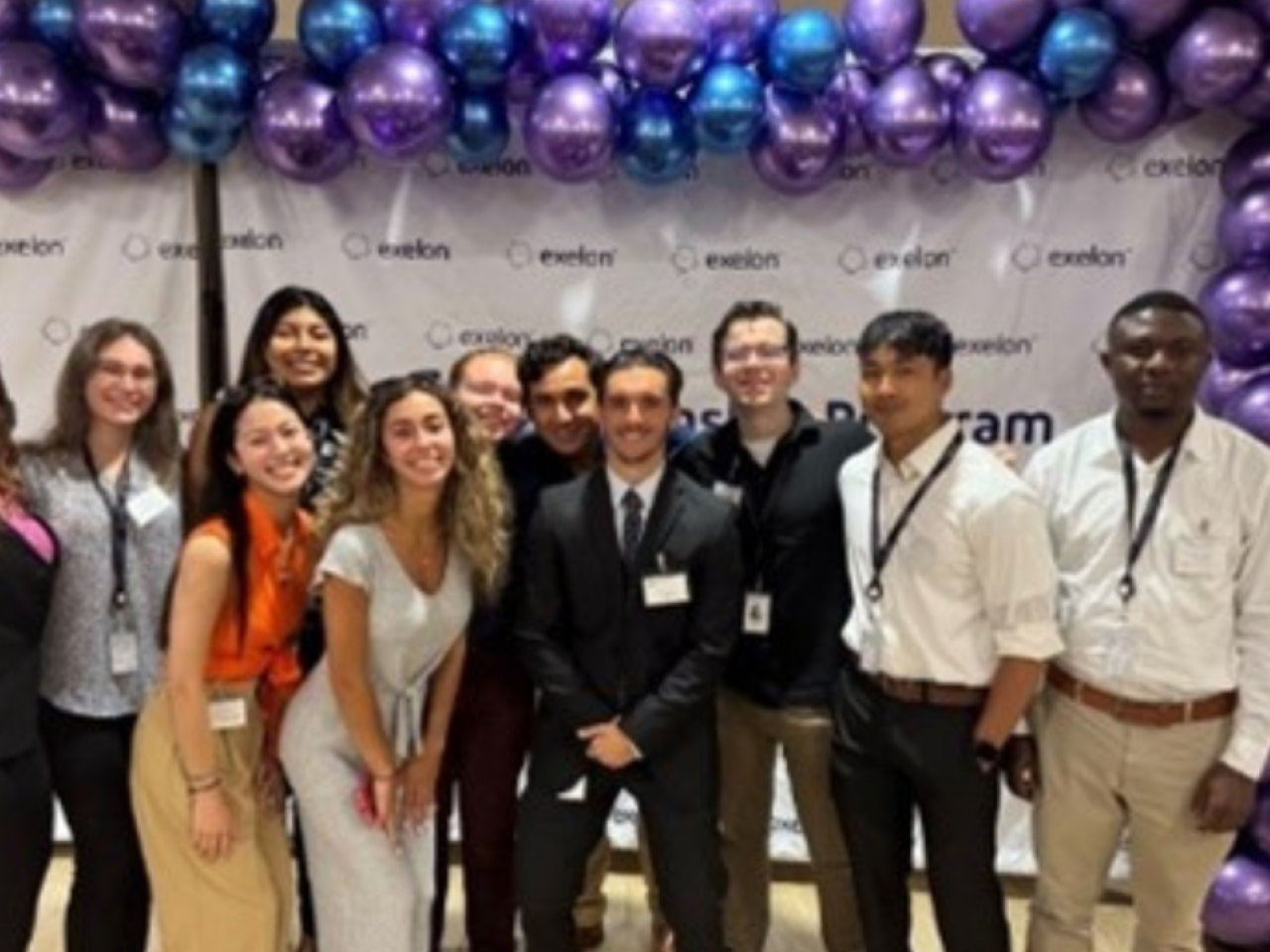 A group of people stood together in front of a balloon arch