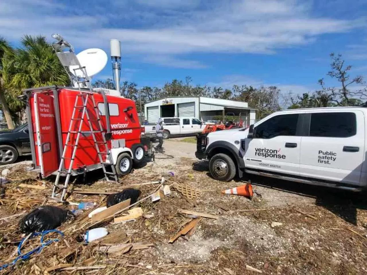 Verizon Response vehicle and trailer parked in an area of high debris and damaged buildings.