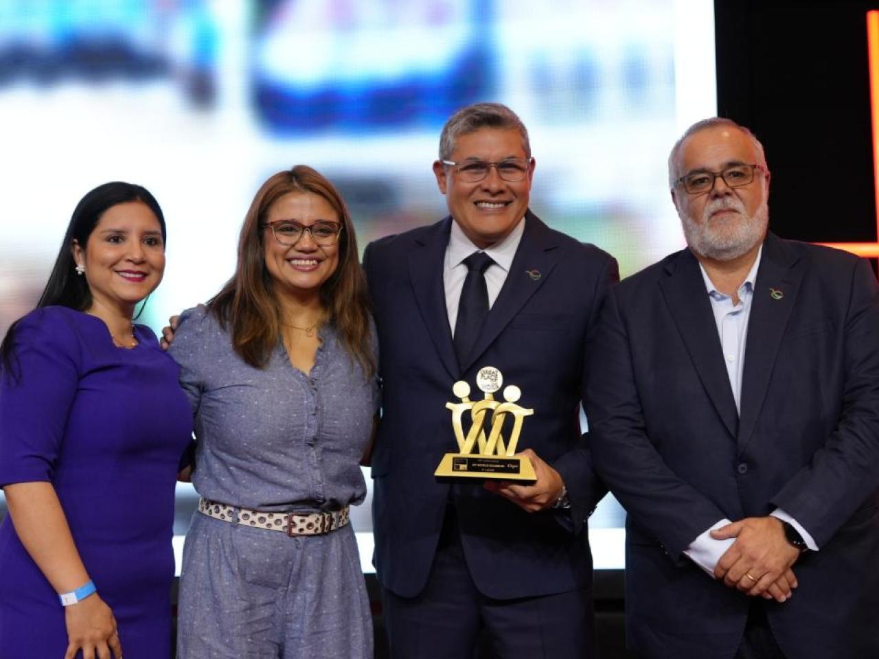 Four people posing, one holding an award