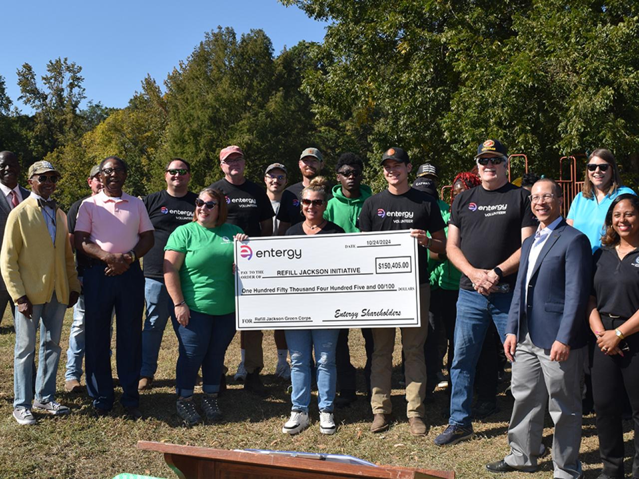 A group posed outside, some holding a large check.