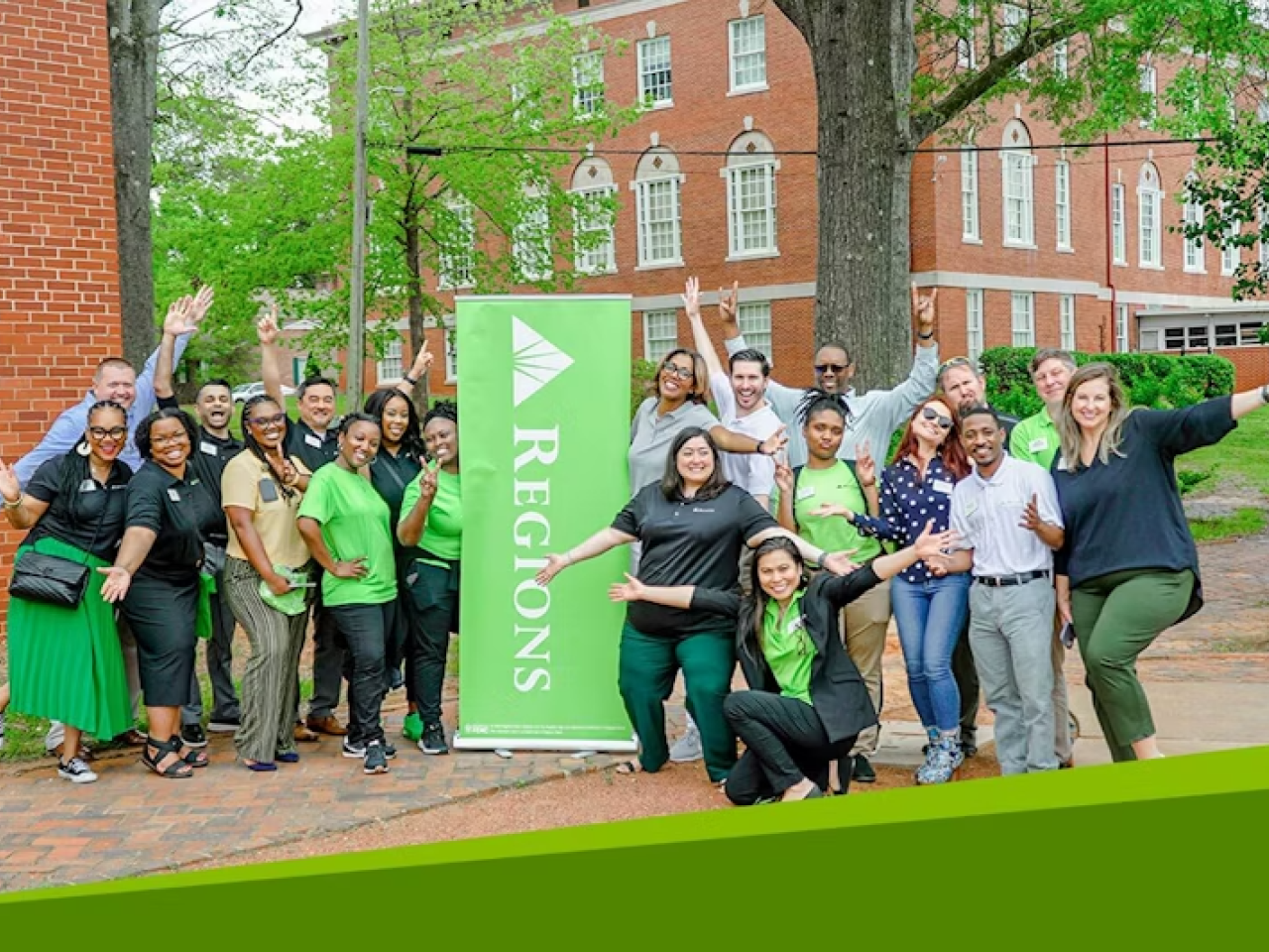 A group of people posing outside next to a Regions banner
