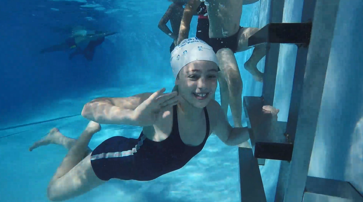 A child swimming under water smiling.