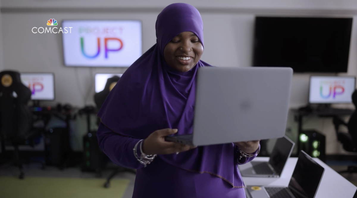 person smiling and holding up a laptop