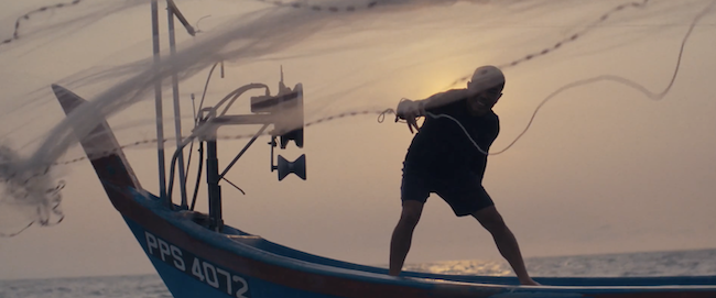 A fisherman casting a net from a fishing boat.