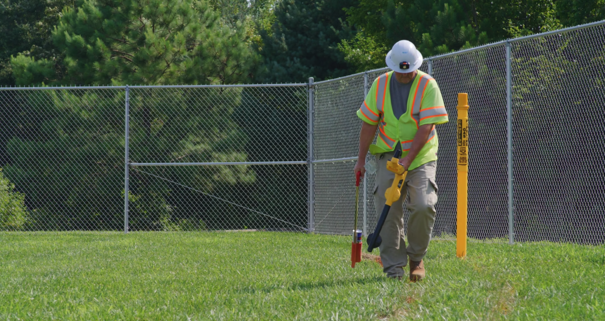 Person wearing safety vest marks ground