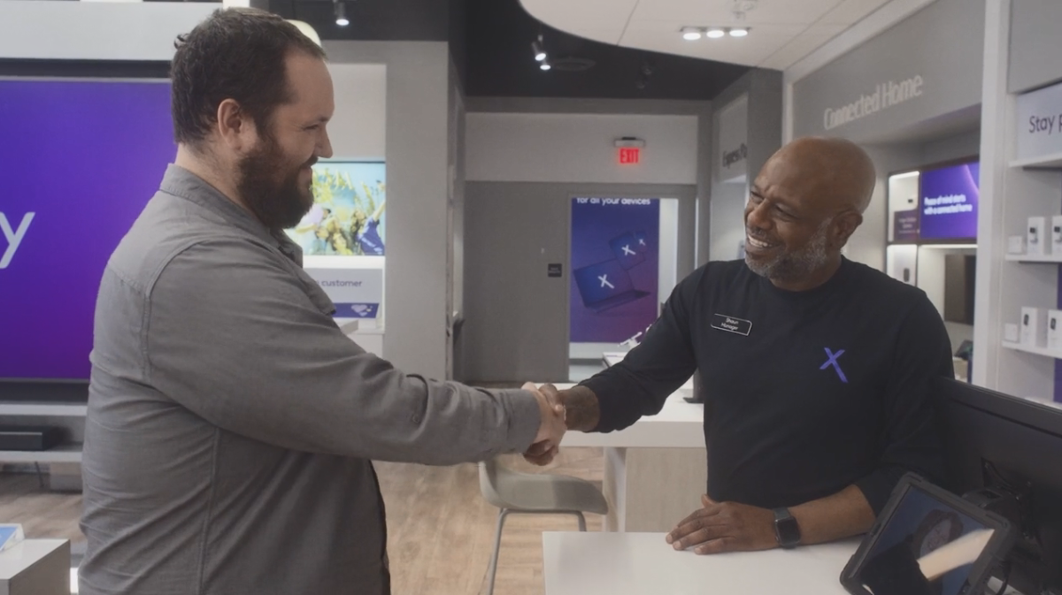 An employee and customer smiling and shaking hands.